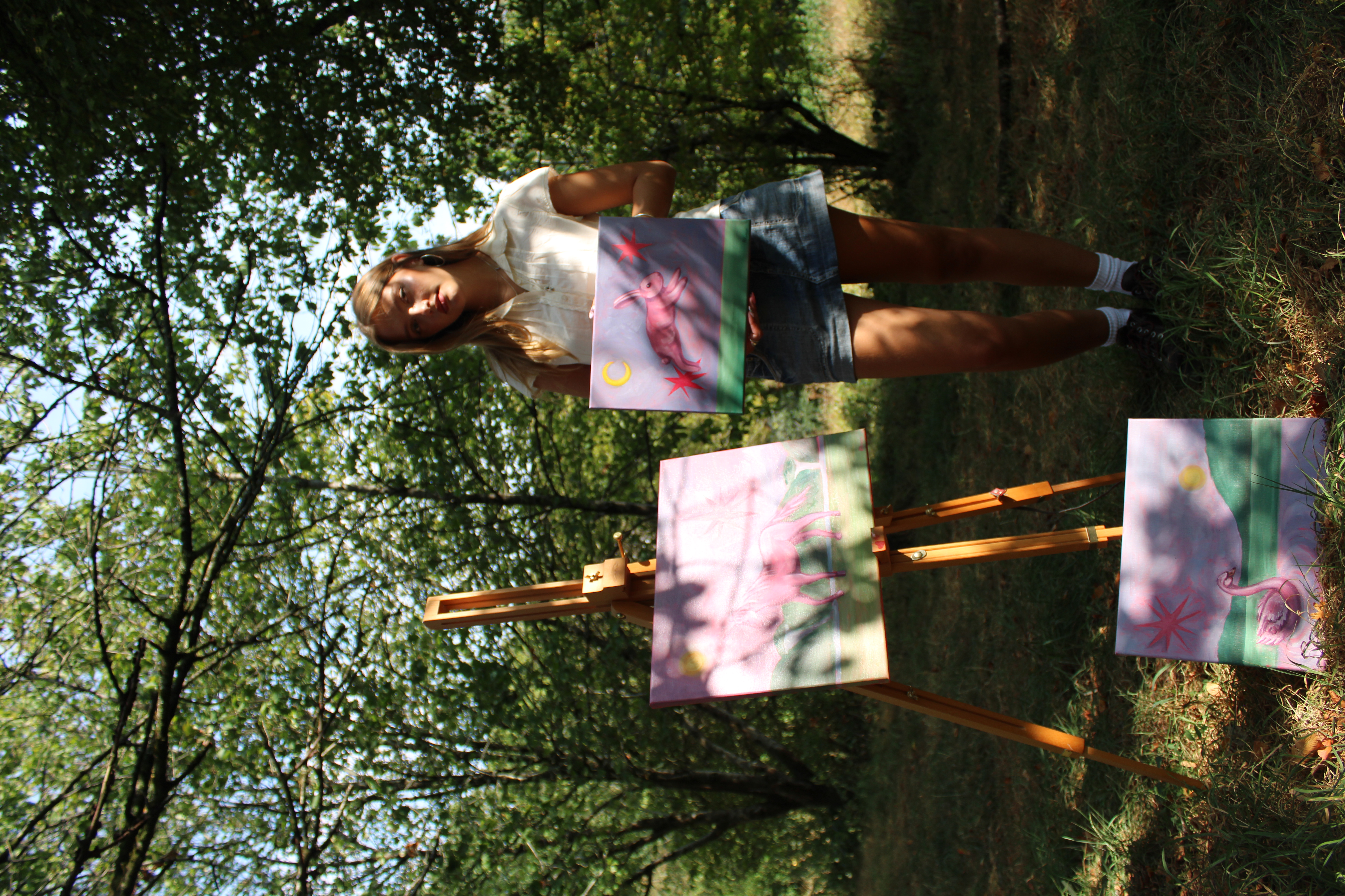 Heidi standing outdoors with her paintings